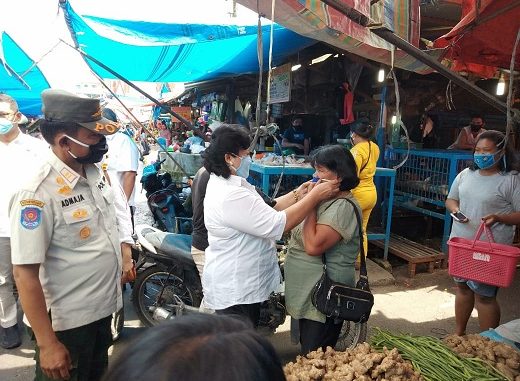 Ket foto: Wakil Bupati karo, Cory.s.sebayang saat memakaikan masker terhadap masyarakat di pusat pasar kabanjahe, foto terkelin bukit.