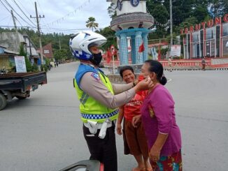 Tampak petugas memasangkan masker ke masyarakat saat gelar operasi Toba 2020