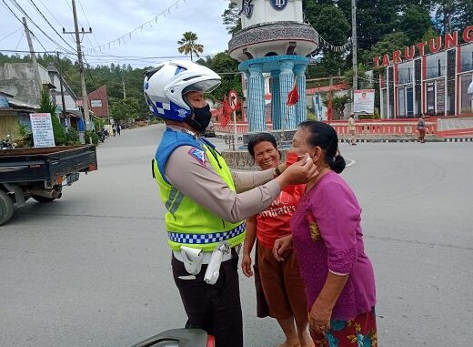 Tampak petugas memasangkan masker ke masyarakat saat gelar operasi Toba 2020