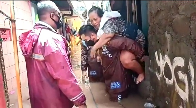 Kapolsek Cilandak Jakarta Selatan AKP Iskandarsyah mengevakuasi warga yang rumahnya terendam banjir, Minggu (21/2/2021). Photo : HumsPolri